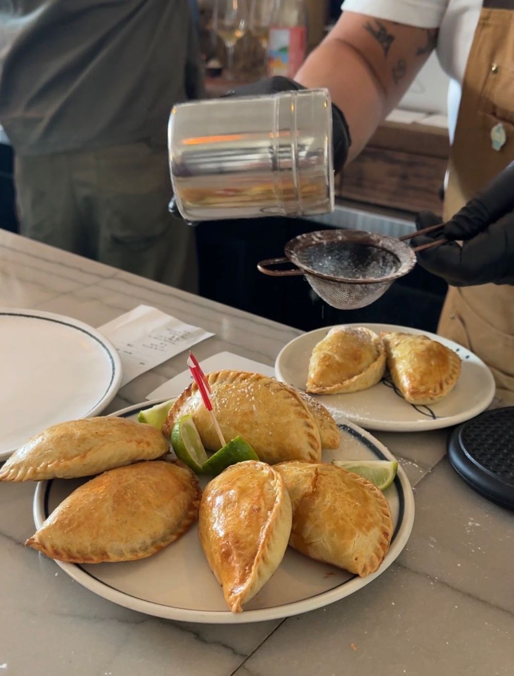 Powdered sugar being dusted over a plate of empanaditas at a pop-up